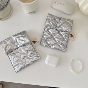 Close-up of silver quilted storage bags with snap closure and heart logo on white desk
