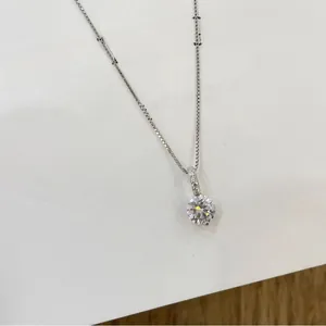 Detailed close-up of a silver box chain necklace with a sparkling round zircon pendant