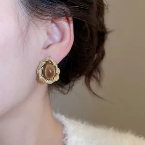 Brown tiger eye stud earrings with twisted gold frame worn by a model in soft light