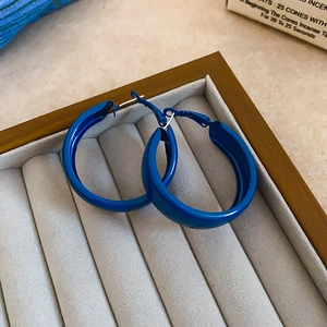 Detailed top view of large Klein blue hoop earrings in a gray velvet jewelry box