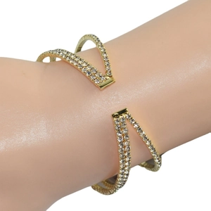 Luxurious gold crossover open bangle featuring sparkling rhinestones on model's wrist