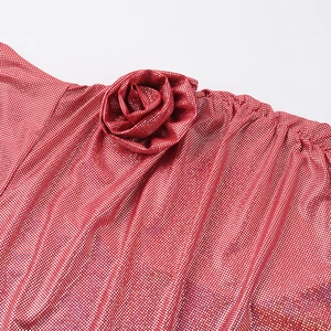 Makroaufnahme von rotem Glitzermaterial mit handgefertigter Rosenfalte am Kleid