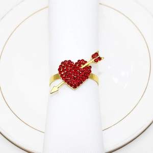 Macro view of gold metal heart and arrow napkin ring with red rhinestones on a white napkin