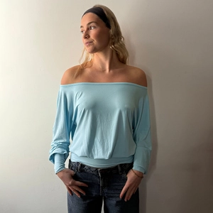 Detail of light blue one-shoulder long sleeve top with elastic waist and slim fit