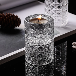 Elegant geometric cut glass candle holder with warm tealight on a black reflective surface