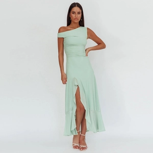 Detail of the high slit and ruffled hem on a light green one-shoulder evening maxi dress