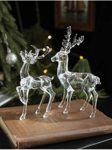 Macro shot of two transparent acrylic reindeer ornaments on vintage books with warm lights