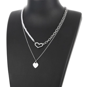 Double-layered necklace with pearls and heart pendants on black jewelry bust display
