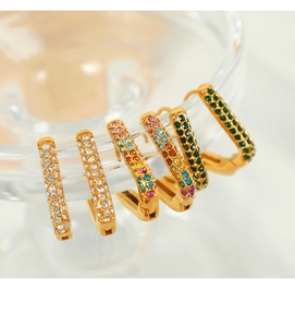 Detailed macro shot of gold plated hoop earrings with emerald and rainbow crystals
