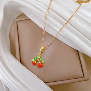 Collier en acier titane avec pendentif cerise en émail sur un coffret bijoux