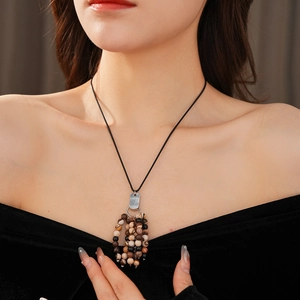 Close-up of vintage beaded necklace with brown stones and leather cord on model