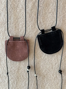 Close-up of brown and black faux leather magnetic glasses holder pendants on beige felt