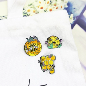Set of 3 colorful honey bee and honeycomb enamel pins on a white canvas tote bag