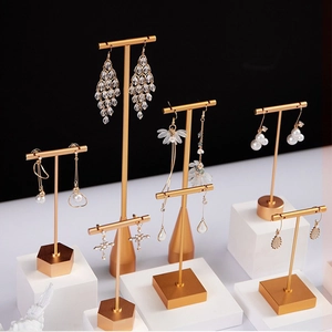Golden T-bar earring display stands in various heights with geometric bases on white blocks