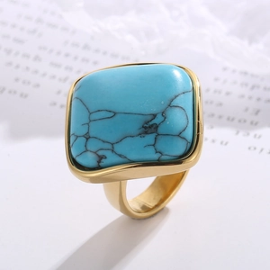 Macro detail of square turquoise stone set in a wide golden stainless steel ring