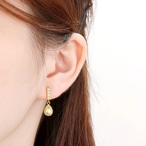 Détail de boucle d'oreille goutte avec perle de nacre et diamants en finition or