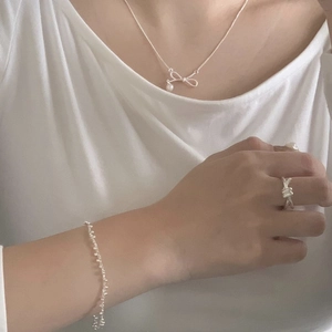 Detail of S925 sterling silver knotted ring and bow necklace set worn by a model