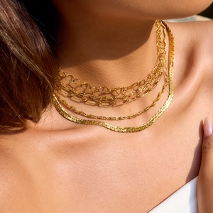 Layered gold snake bone and paperclip chain necklace set displayed on a fashion model
