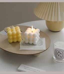 Macro detail of bubble cube scented candles in white and yellow colors lit in cozy setting