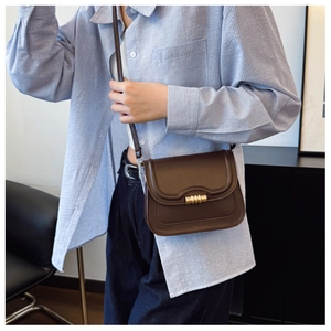 Sac à bandoulière en cuir marron avec boucle dorée porté pour voir la taille et le profil
