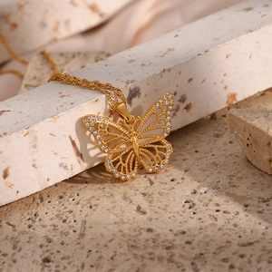 Macro detail of gold butterfly pendant with sparkling cubic zirconia on stone background