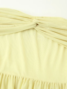 Close-up of yellow mesh dress detail with elegant front knot and soft pleated textures