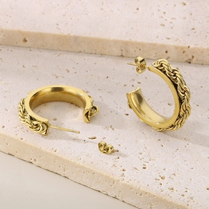 Elegant gold twisted rope C-shaped hoop earrings on a textured marble stone background