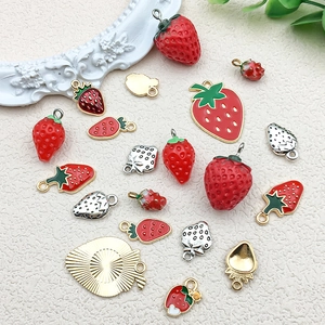 Detailed view of 3D red strawberry alloy pendants with oil dripping for DIY jewelry