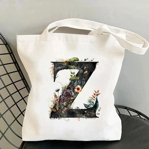 Close-up of floral letter Z print on off-white canvas tote bag against a mesh chair