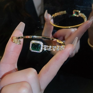 Detail of gold open cuff bracelet featuring a large square emerald zircon and pave crystals