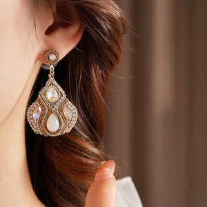 Détail macro de boucles d'oreilles vintage en or avec zircons blancs et perles de nacre