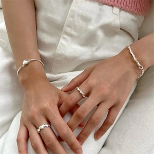 Close-up of S925 sterling silver woven bracelets and minimalist heart rings on wrist
