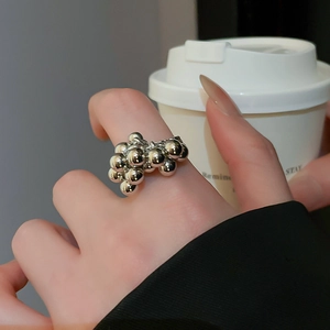 Macro shot of a silver stacked bead ring worn by a hand holding a white coffee cup