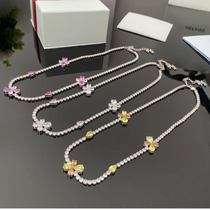 Détail de trois colliers avec pendentifs trèfles étincelants en rose, blanc et vert