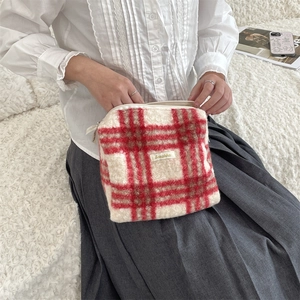 Detail van rood-wit geruite pluche make-uptas met zachte textuur en handige ritssluiting