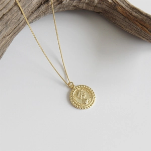 Collier en or avec pendentif pièce Elizabeth II sur fond blanc élégant et épuré