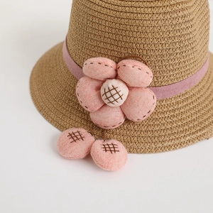 Kids wide brim straw sun hat with large pink fabric flower and decorative hanging poms