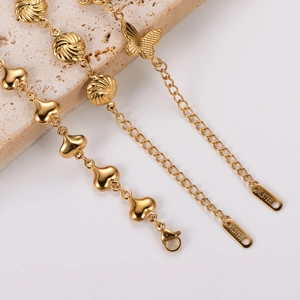 Gold stainless steel bracelet with butterfly and heart charms on marble base