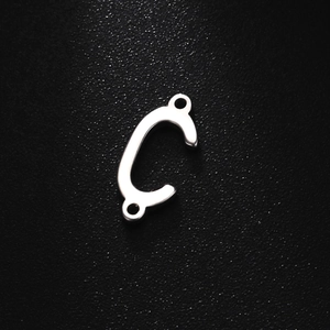 Close-up of silver stainless steel C-shaped jewelry connector with dual holes on black