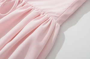 Vue détaillée de la texture du tissu plissé rose et des coutures fines d'une robe longue