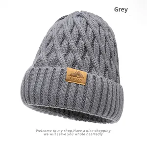 Detail of grey cable knit winter beanie with ribbed cuff and mountain leather patch