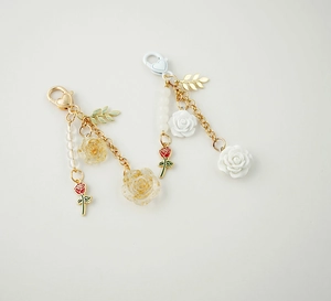 Detail of rose resin keychain charms with gold and silver hardware on white background