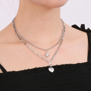 Close-up of layered silver necklace with star and heart pendants on a model's collarbone