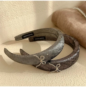 Close-up of velvet bow headbands with silver beads and handmade labels in grey shades