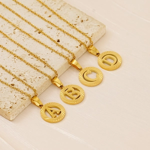 Detail of 18K gold stainless steel round coin pendants with embossed A, B, C, D letters