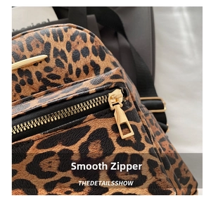 Detailed macro view of smooth gold zipper and classic leopard print fabric on a backpack
