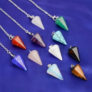 Assorted natural crystal hexagonal cone pendants with metal chains on blue fabric