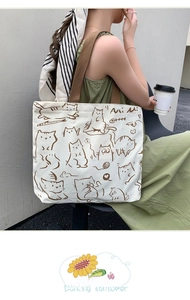 Detail of canvas tote bag showing the hand-drawn cat illustration and brown woven strap
