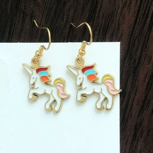 Detail of colorful unicorn earrings with enamel mane on a white display card