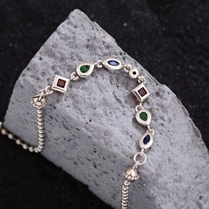 Chic silver necklace with vibrant colorful zircon stones on a grey rock background